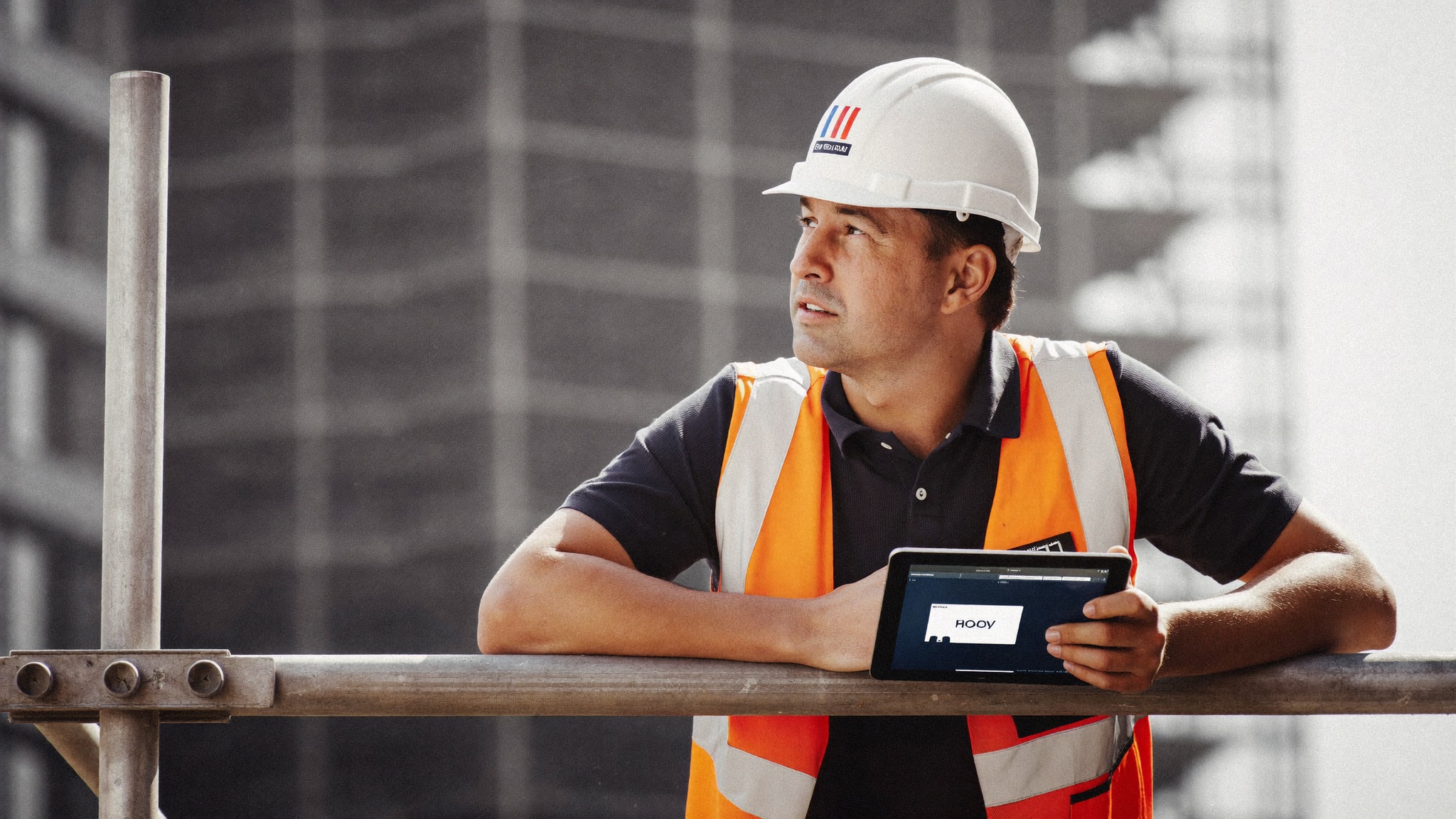 Jefe de obra consultando una tablet apoyado en el andamio