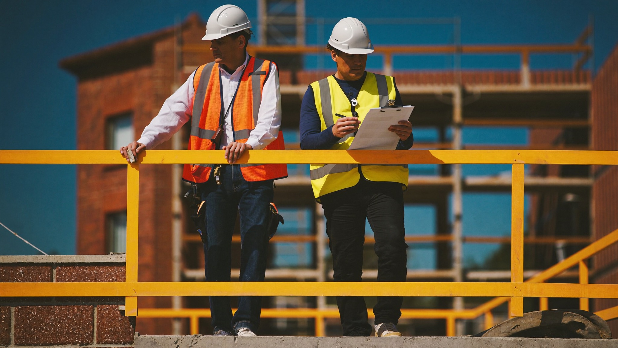 Dos técnicos revisando la protección de borde de un forjado con una lista de comprobación